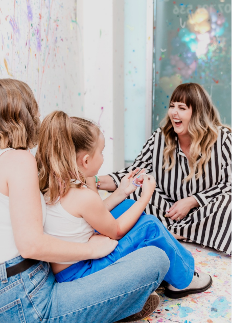 Kayla sitting with young people in a bright creative space, laughing and connecting